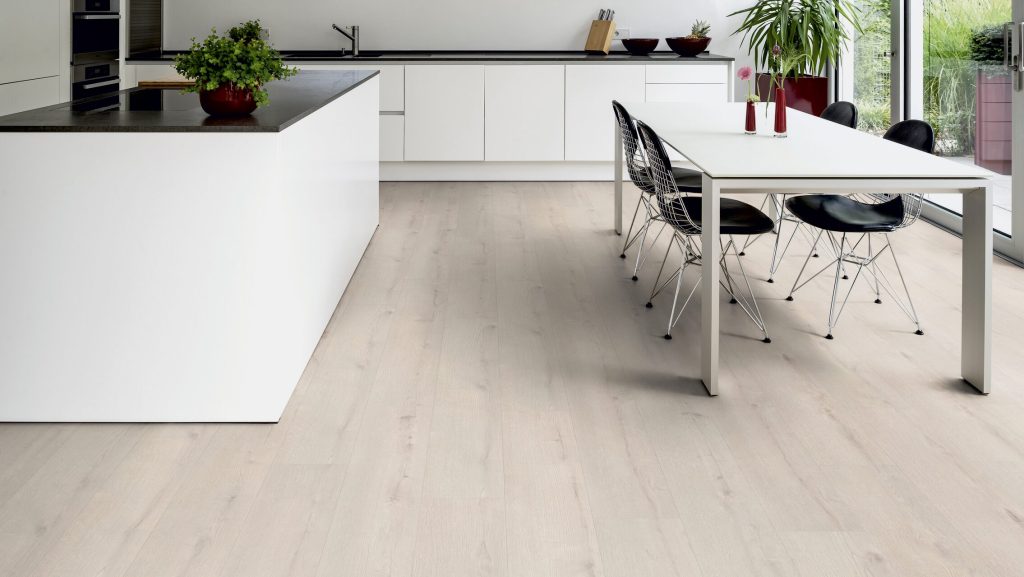 Világos tölgy mintázatú SPC padló modern fehér konyhában étkezőasztallal és fekete design székekkel.